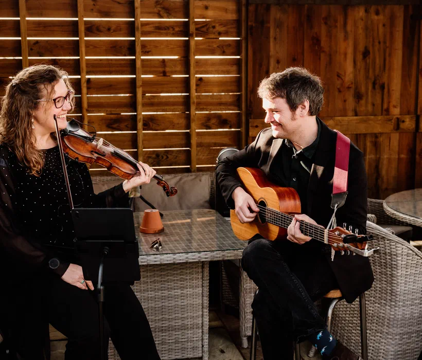 Sarah and Tom playing violin and guitar together at golden hour