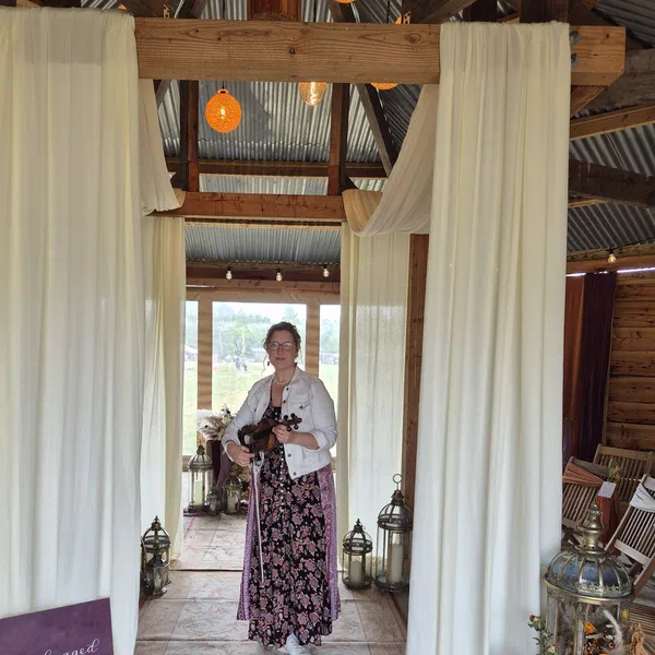Sarah performing in a draped barn doorway at a wedding