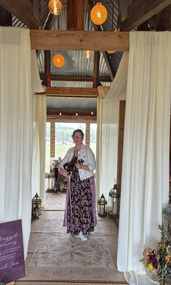 Sarah performing in a draped barn doorway at a wedding