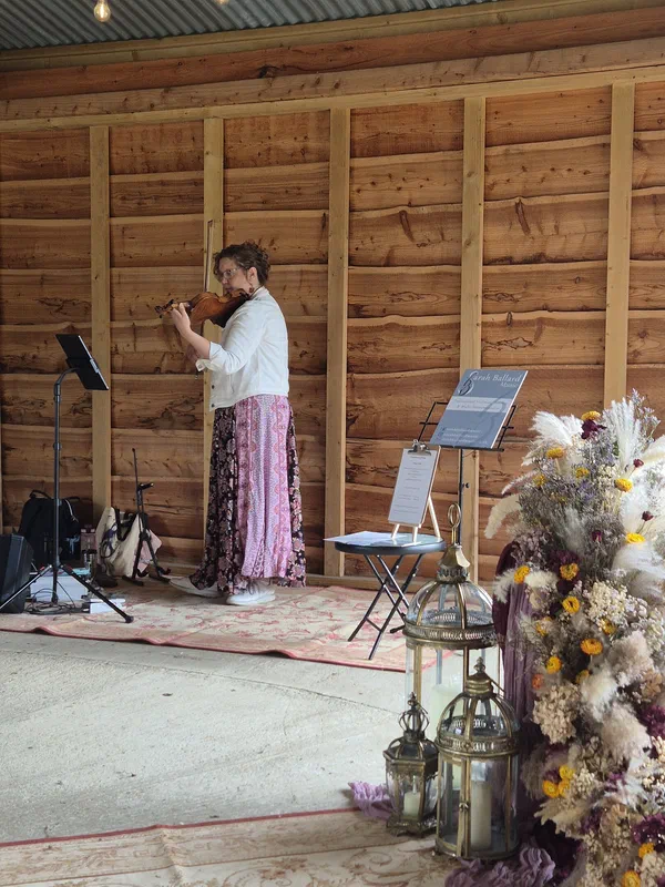 Sarah performing solo violin in a decorated barn