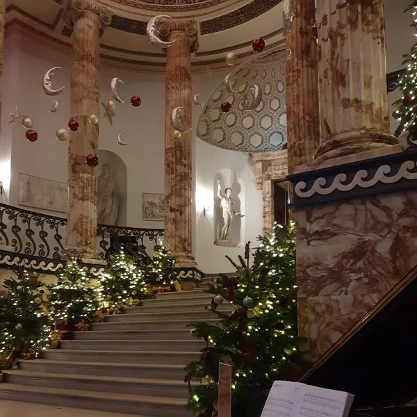 Grand marble staircase decorated for Christmas with piano