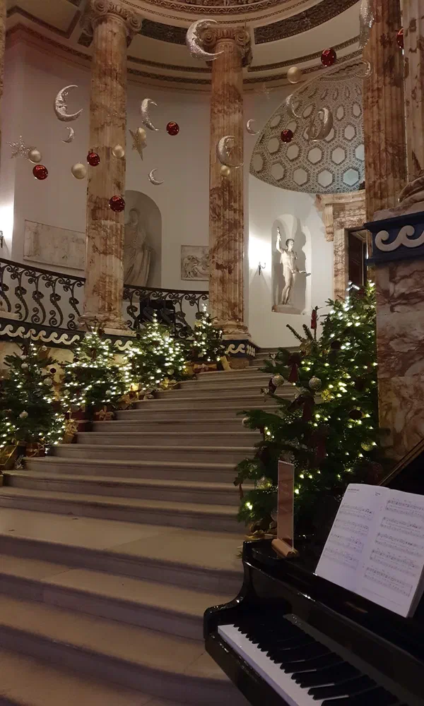 Grand marble staircase decorated for Christmas with piano