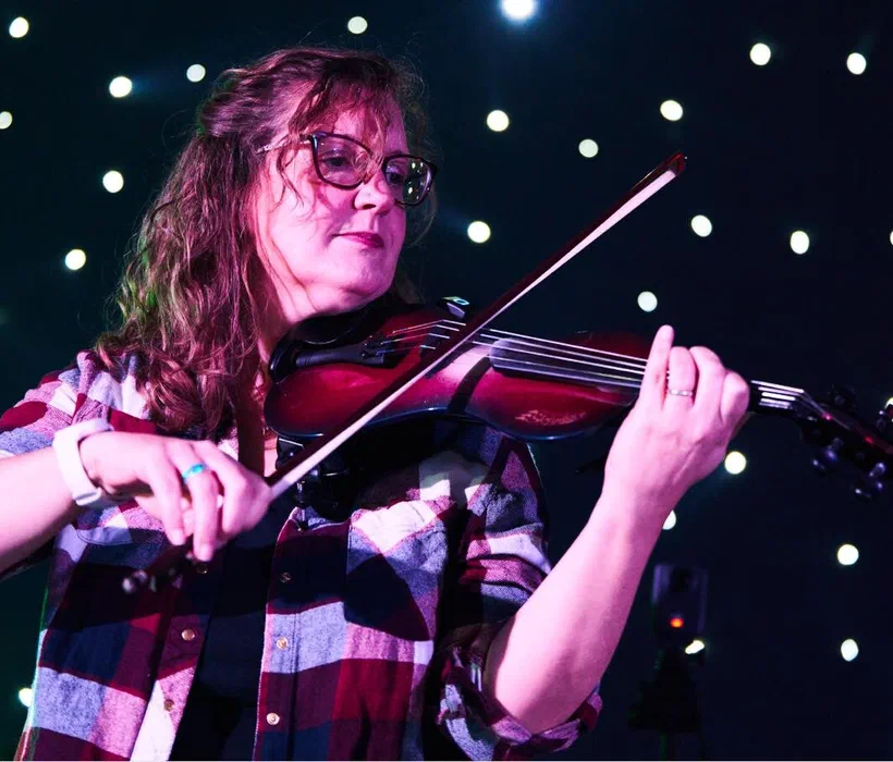 Sarah performing electric violin under moody stage lighting