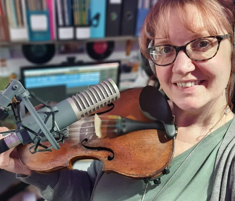 Sarah's home studio — violin beside a studio microphone with a DAW and vinyl shelf behind