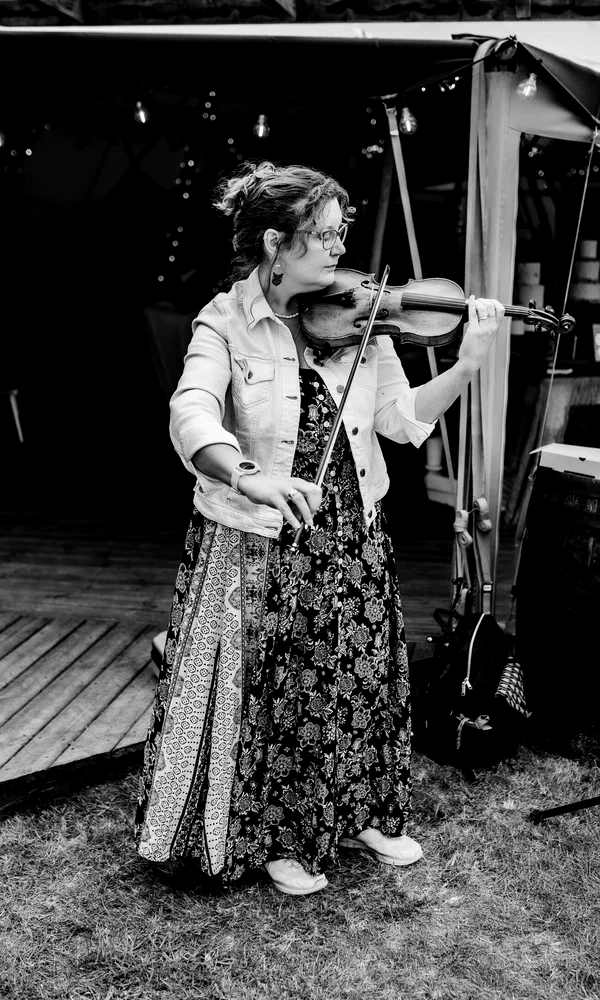 Sarah performing violin at an outdoor tipi wedding, black and white